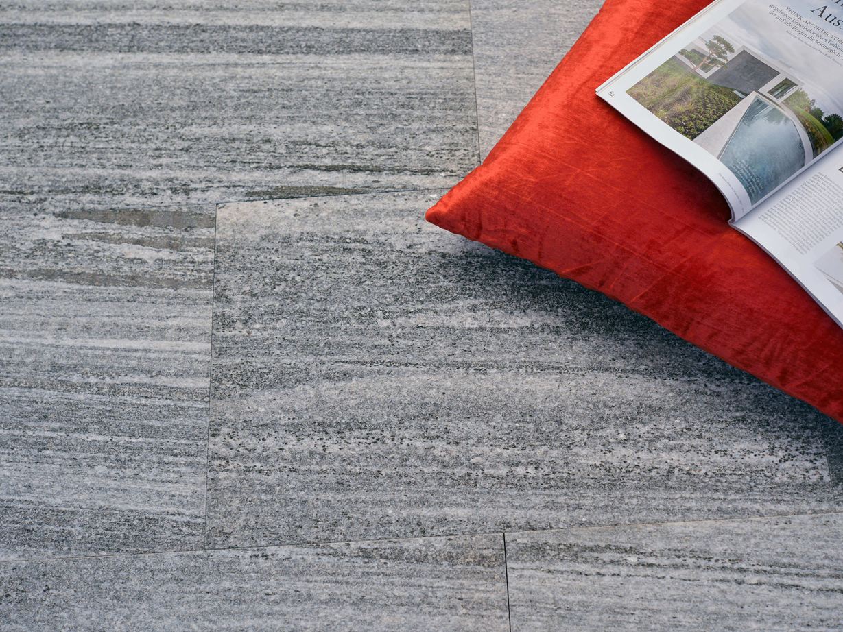 Gneisplatten Urban Grey Line mit orangefarbenem Kissen und Zeitschrift