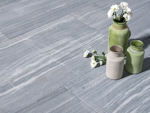 Drei Vasen mit Blumen auf Kalksteinplatten in hellem Grau mit weißen Maserungen
