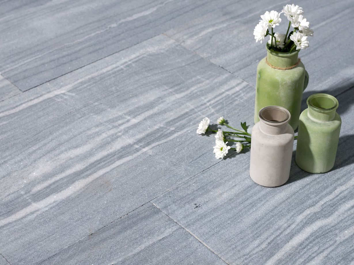 Drei Vasen mit Blumen auf Kalksteinplatten in hellem Grau mit weißen Maserungen