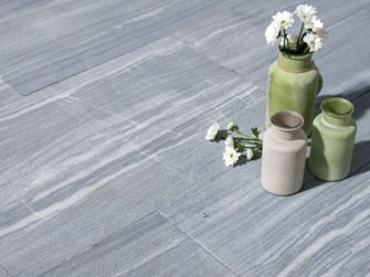 Drei Vasen mit Blumen auf Kalksteinplatten in hellem Grau mit weißen Maserungen