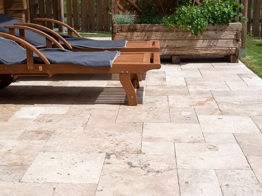 Terrasse mit Liegestühlen und Travertinboden im Abendlicht