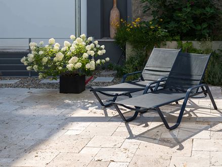 Zwei Liegestühle und Blumenstock auf getrommelter Travertinplatte Rustic