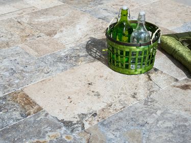 Grüner Flaschenkorb auf Terrassenplatten Travertin Silver