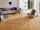 Graue moderne Couch mit Sessel auf Feinsteinzeugfliesen in Holzoptik Urban Honey in hellem Wohnzimmer