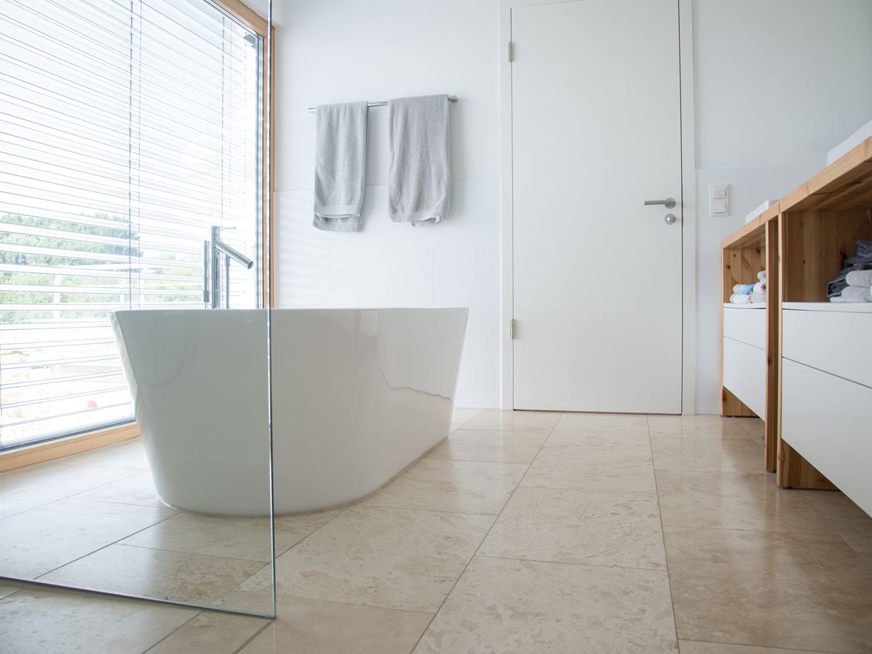 Modernes Bad mit Travertin Classic Light und freistehender Badewanne