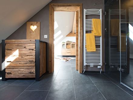 Rustikales Badezimmer mit Holzmöbeln, dunklen Natursteinfliesen aus Schiefer als Bodenbelag und einer Dachschräge