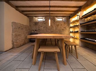 Weinkeller mit rustikalen Holzmöbeln, Weinregalen und grauen Sandsteinplatten als Bodenbelag
